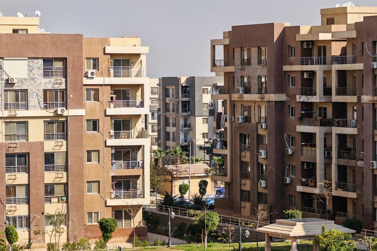 A modern residential apartment complex with balconies and landscaped green spaces, representing a homeowners' community in Karnataka.