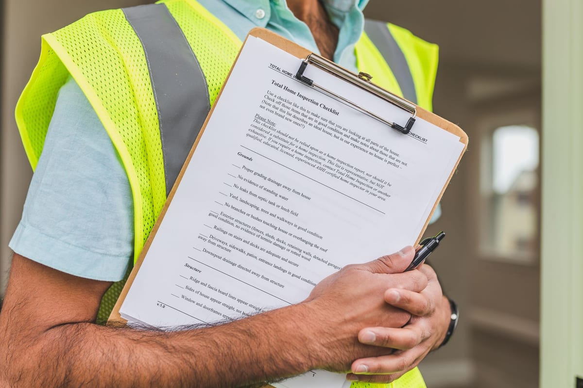 A person reviewing construction project documents and a building plan on a desk, representing due diligence on a residential project before buying